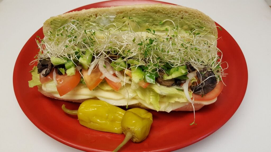 Fresh Vegetarian Sandwich loaded with smashed avocado, mushrooms, cucumbers, and cheese at Tummy Stuffer Aliso Viejo